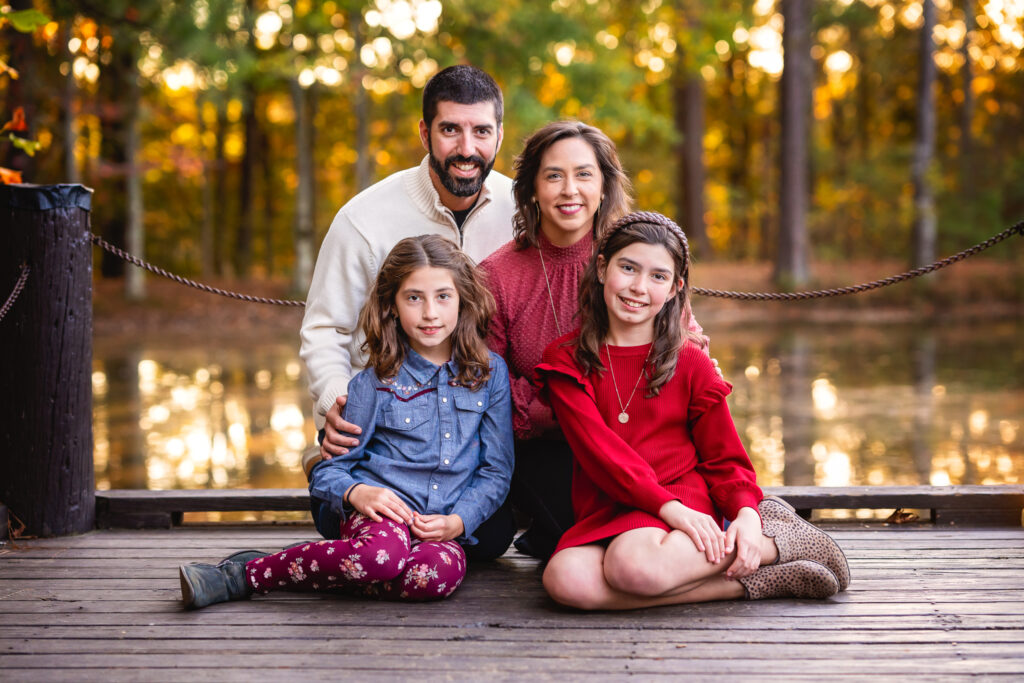 A family of four is sitting on a deck by a small lake at Line Creek in Peachtree City, GA.