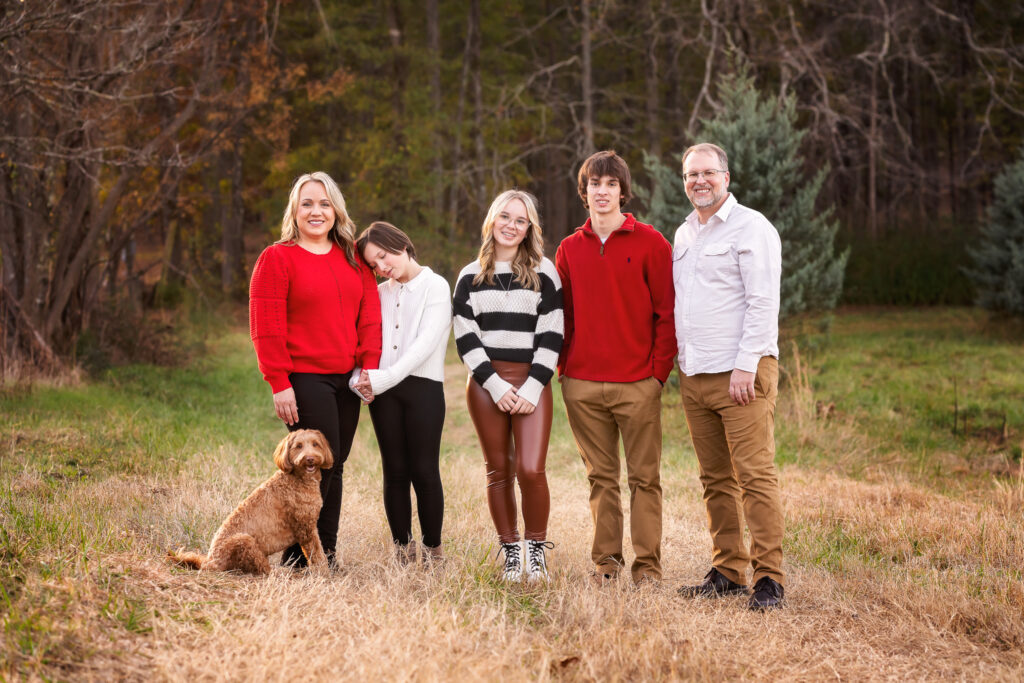 This family of 5 is smiling with their dog as they pose for their family photography session at Minter's Farm.